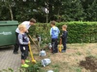 Kinder pflanzen gemeinsam Bäume.