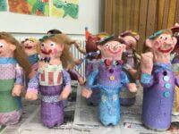 Viele bunte lächelnde Gips-Puppen nebeneinander, von Kindern kreativ gestaltet