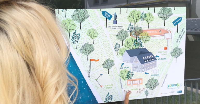 Eine Person mit blonden Haaren zeigt auf einen Ort auf der illustrierten Geländekarte der youcoN 2022