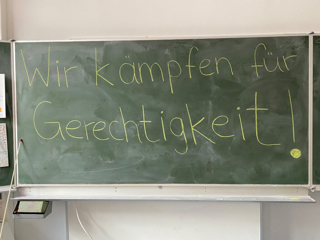 Schultafel mit der Aufschrift "Wir kämpfen für Gerechtigkeit!"