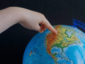 Spenden für Kinder: Ein Kinderfinger zeigt auf einem Globus auf Nordamerika (c) summa/Pixabay