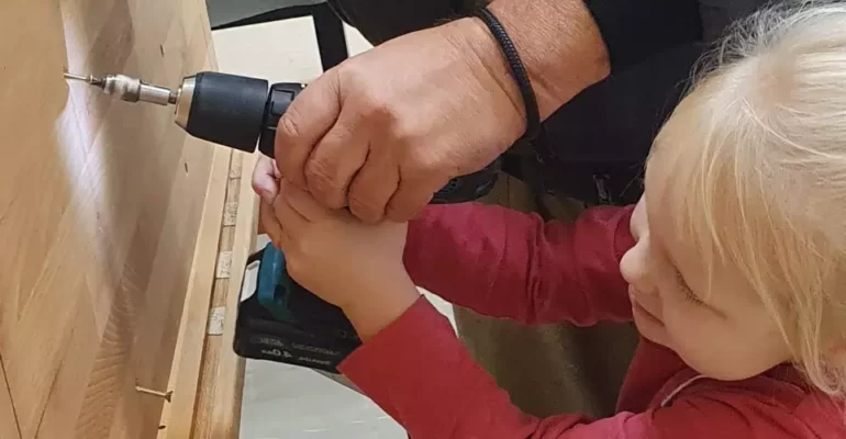 Ein Kind bohrt eine Schraube in Holz - Förderfonds Handwerk der Stiftung Bildung
